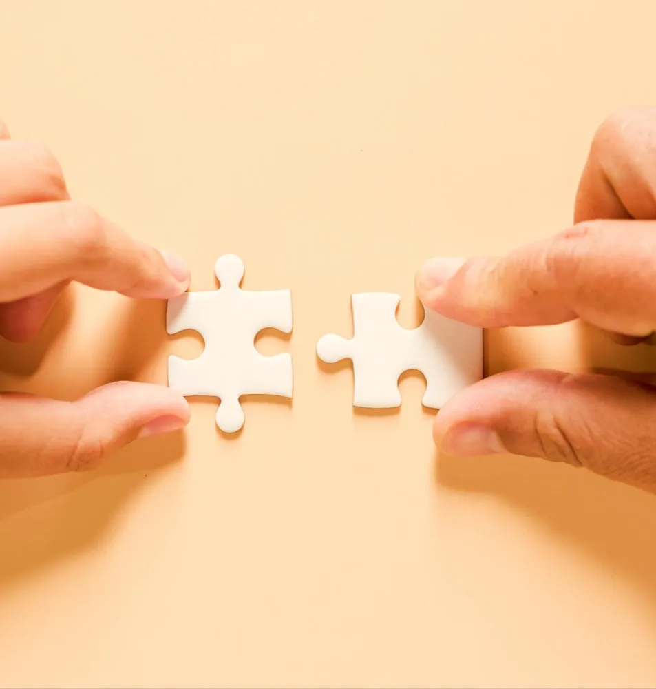 Dua tangan menyatukan potongan puzzle